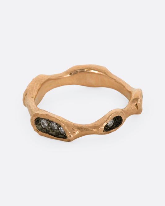 Bead set diamonds peak out from the moody crevices in this undulating rose gold band.