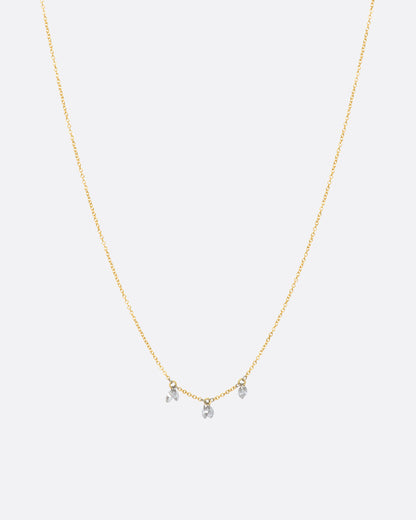 A yellow gold cable chain necklace with three stations of two marquise diamonds. View from the front, full necklace.