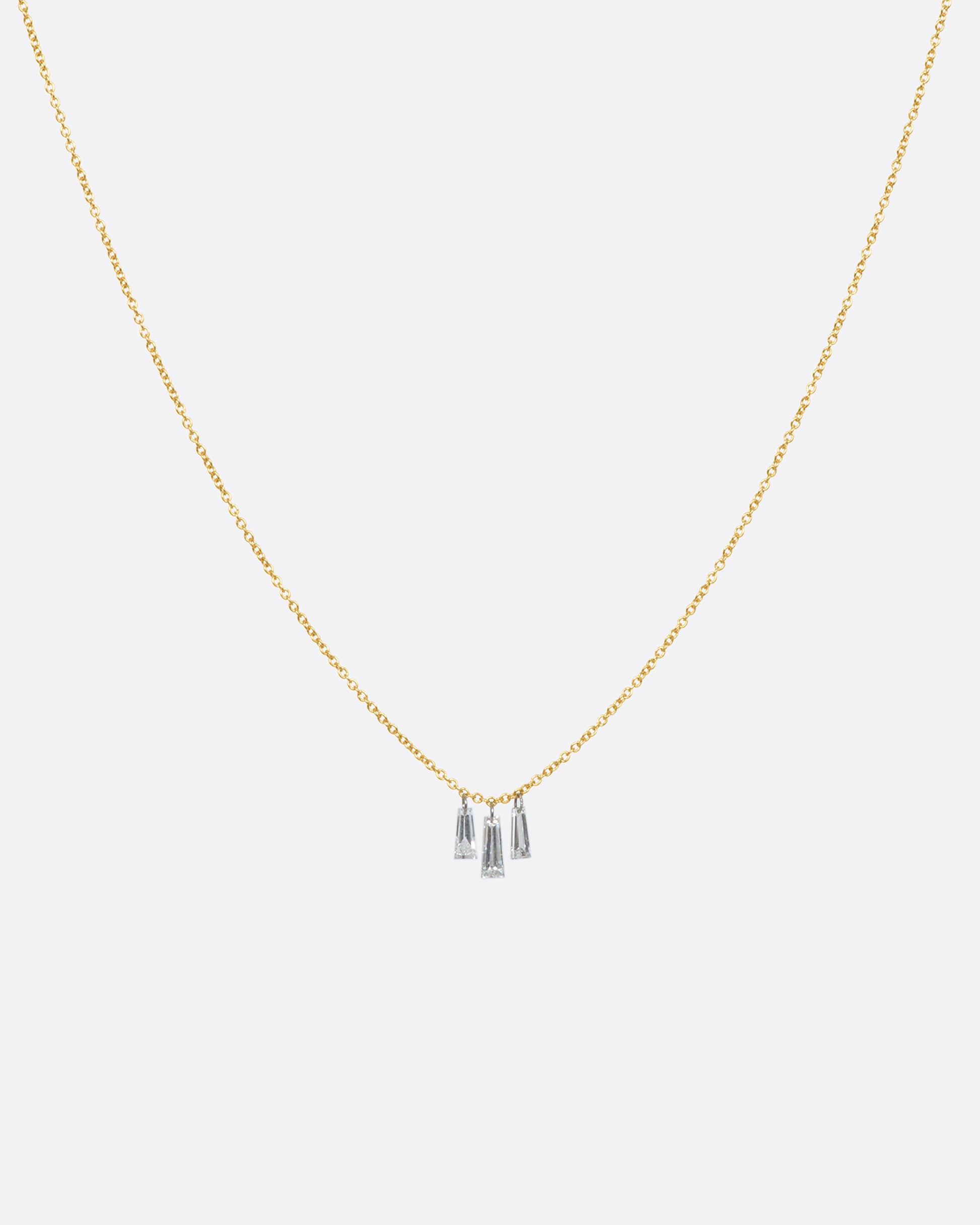 A yellow gold cable chain necklace with three hanging diamond baguettes. View from the front.