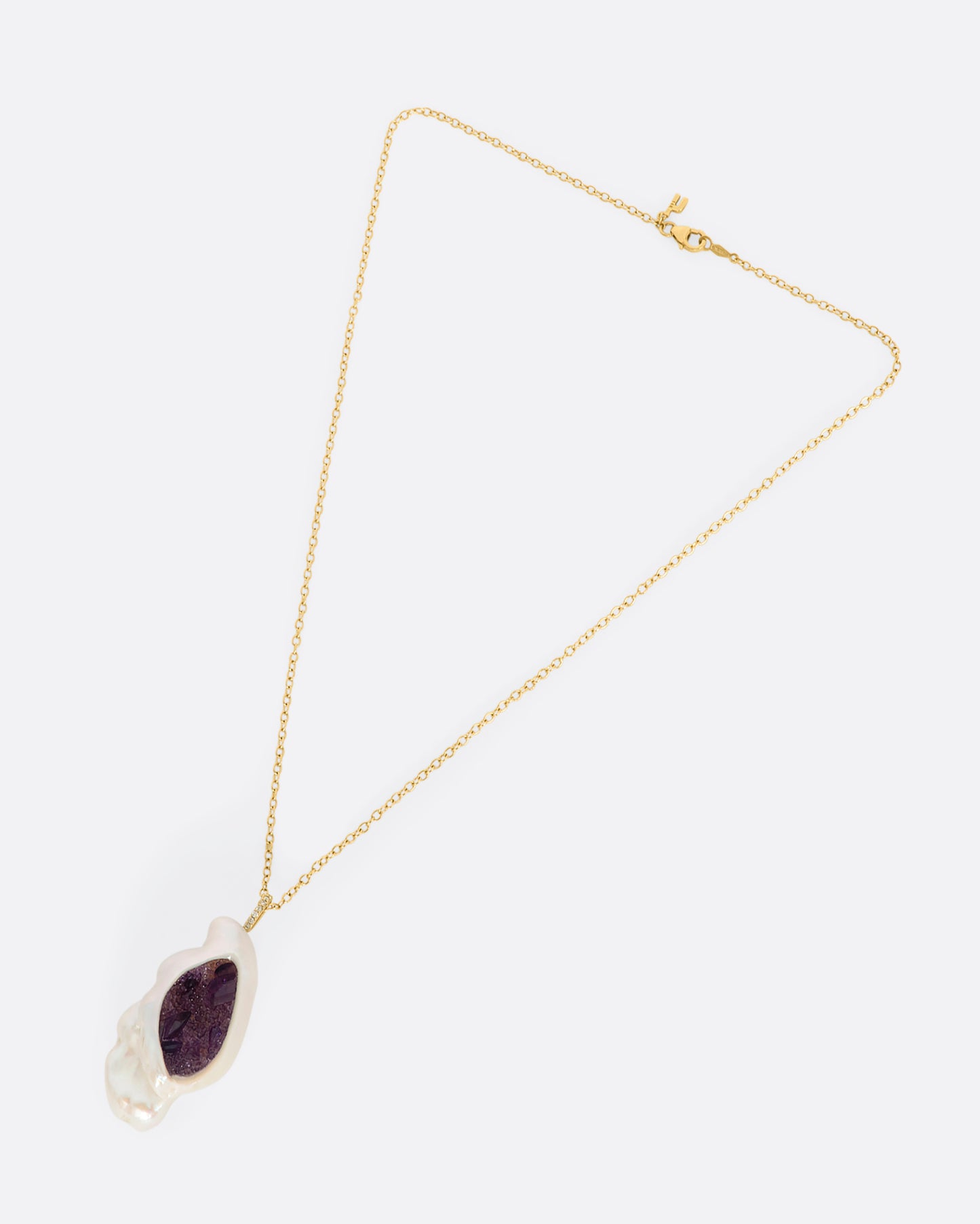 A yellow gold necklace with a hollowed out pearl pendant filled with amethysts and a pave diamond bale. Shown laying flat.