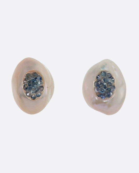 A pair of yellow gold earrings with hollowed out pearls filled with sapphires. Shown from the front.