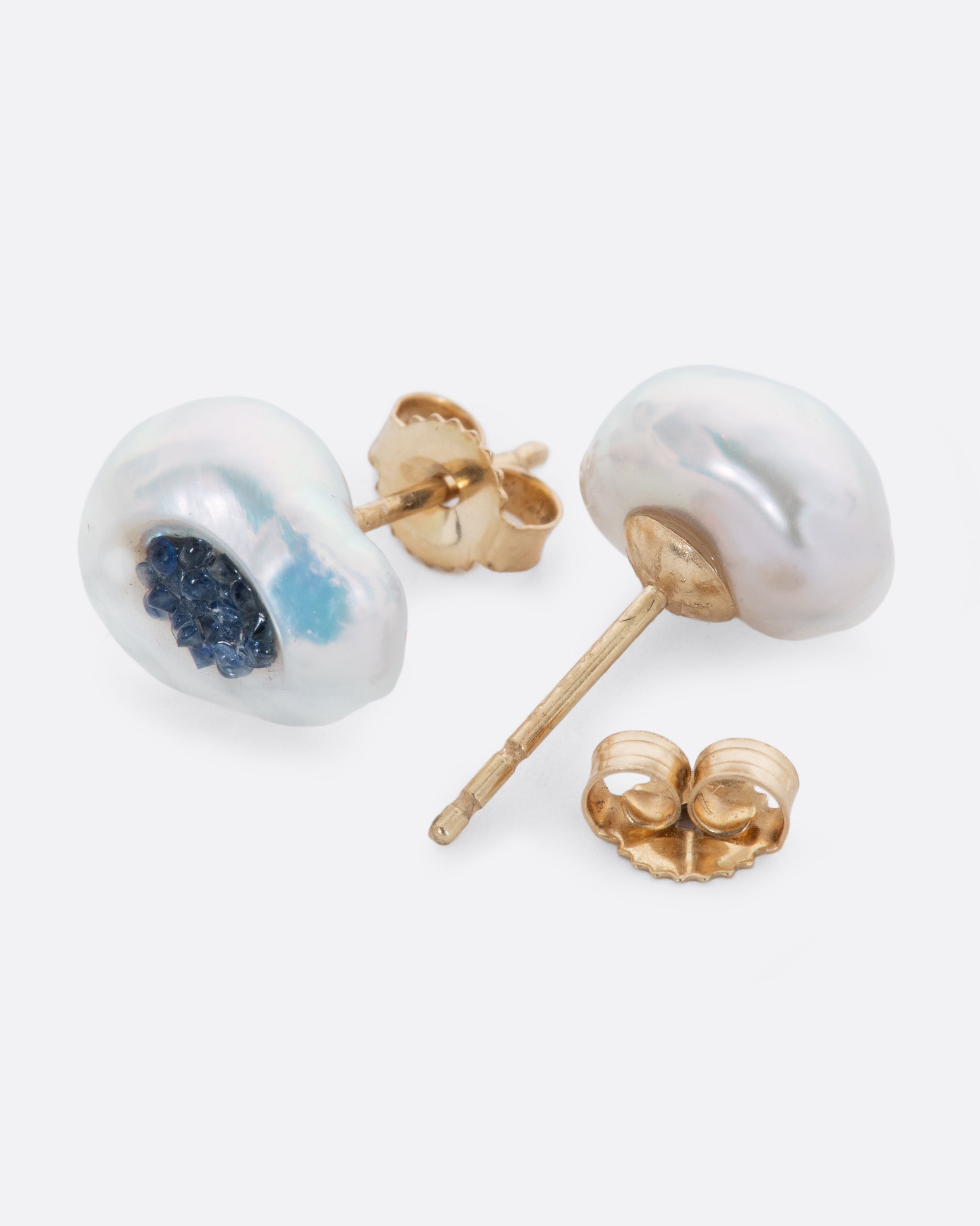 A pair of yellow gold earrings with hollowed out pearls filled with sapphires. Shown from the front and back alternating.