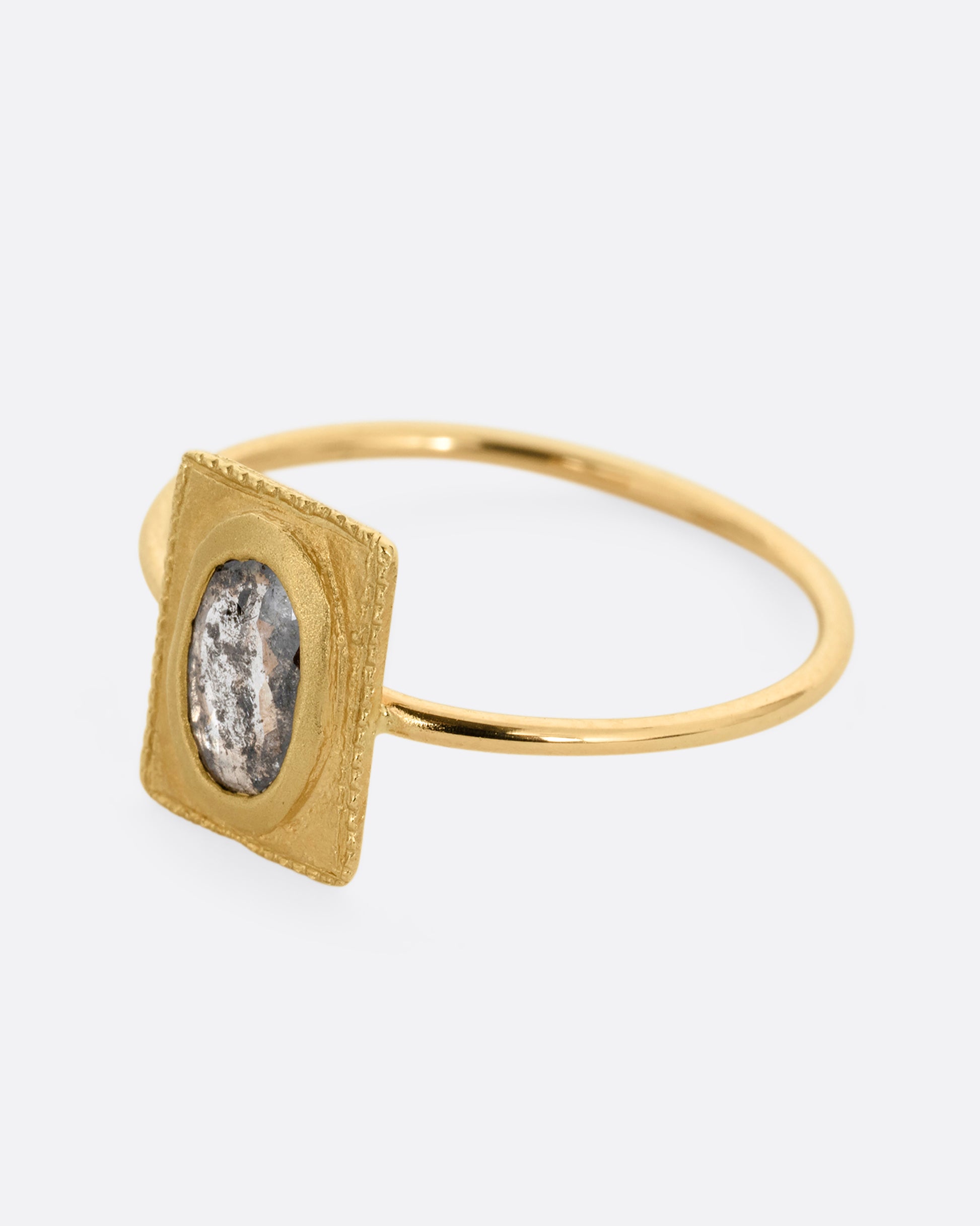 A yellow gold ring with an oval rose cut diamond in a rectangular setting. Shown from the side.
