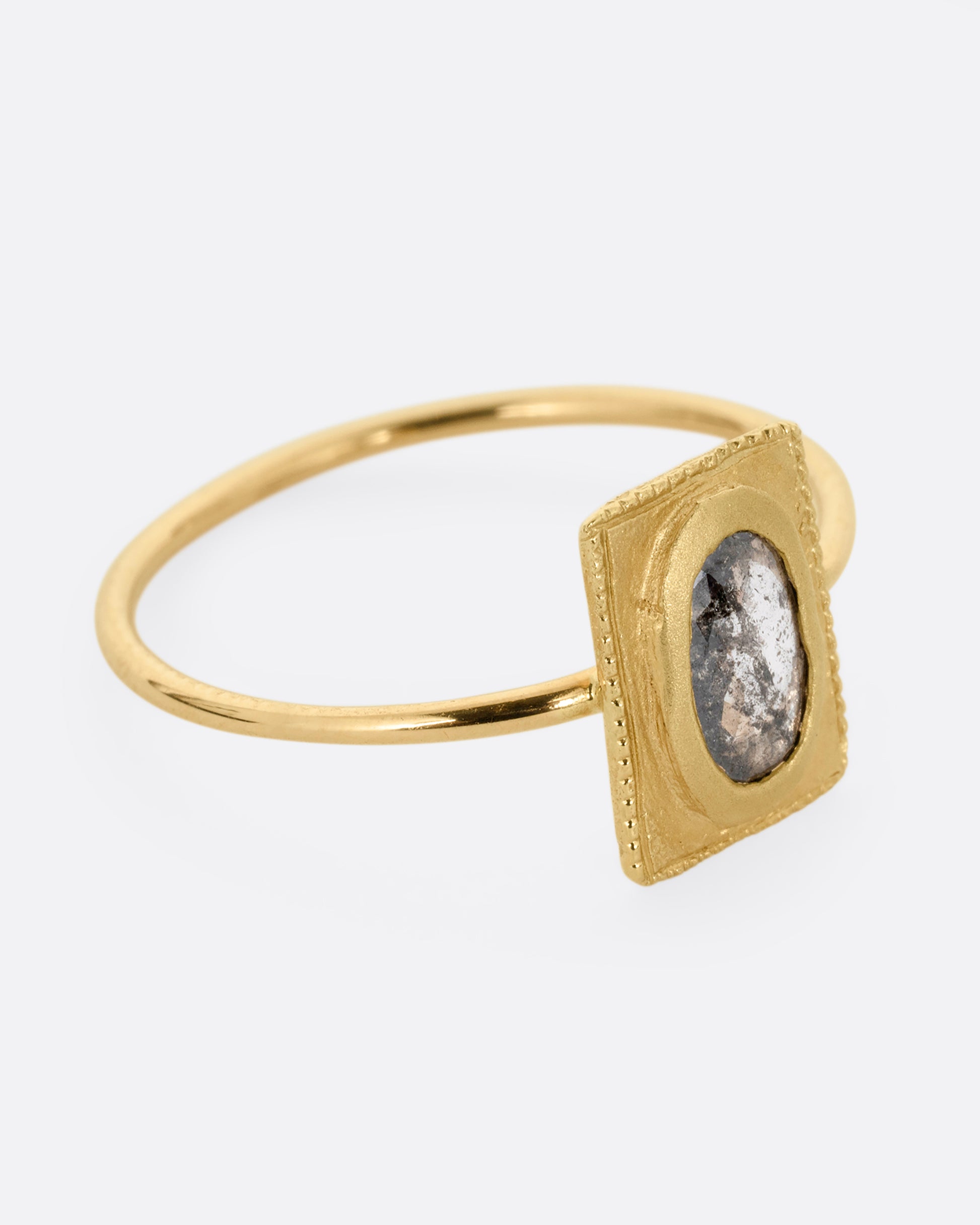 A yellow gold ring with an oval rose cut diamond in a rectangular setting. Shown from the side.
