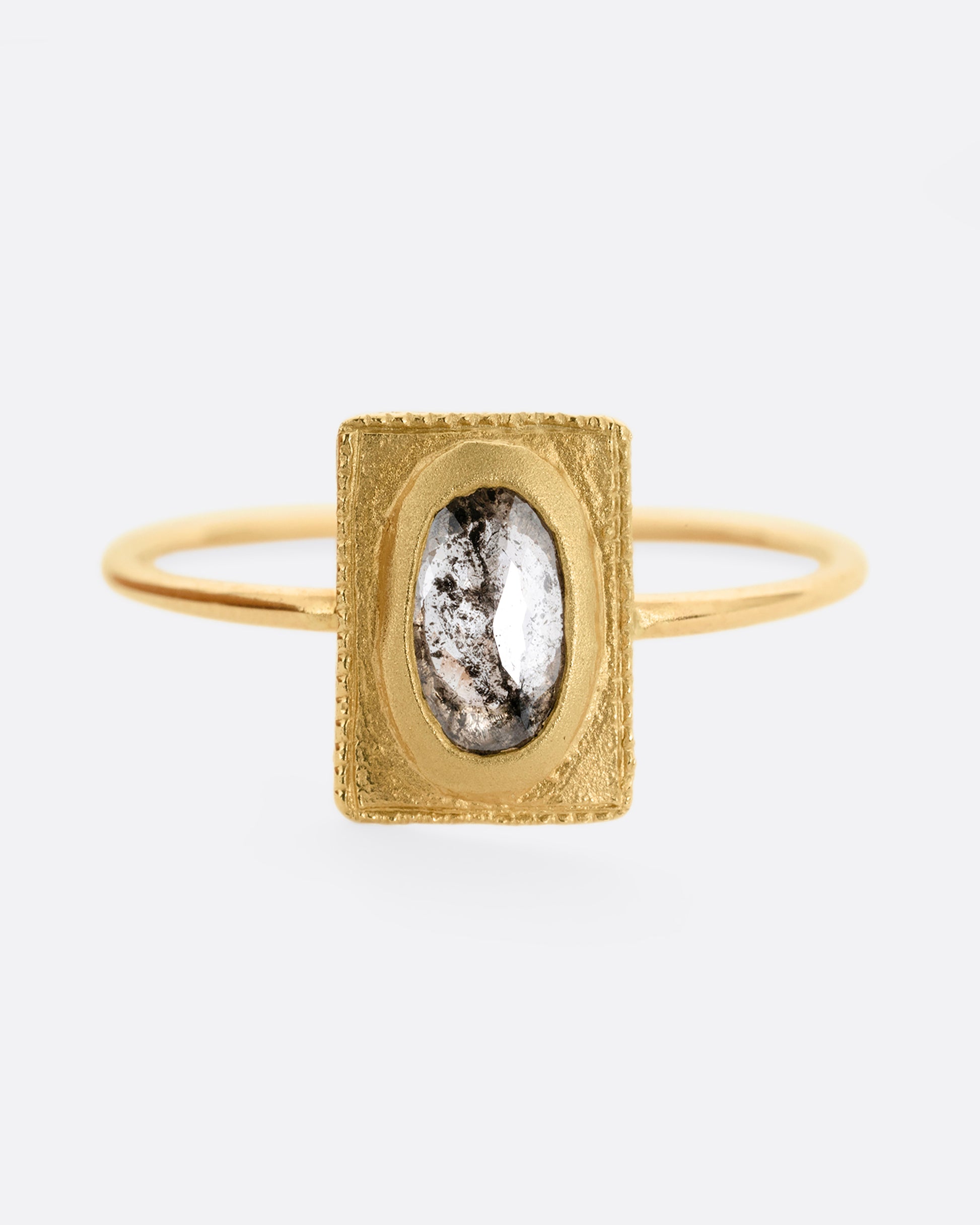 A yellow gold ring with an oval rose cut diamond in a rectangular setting. Shown from the front.