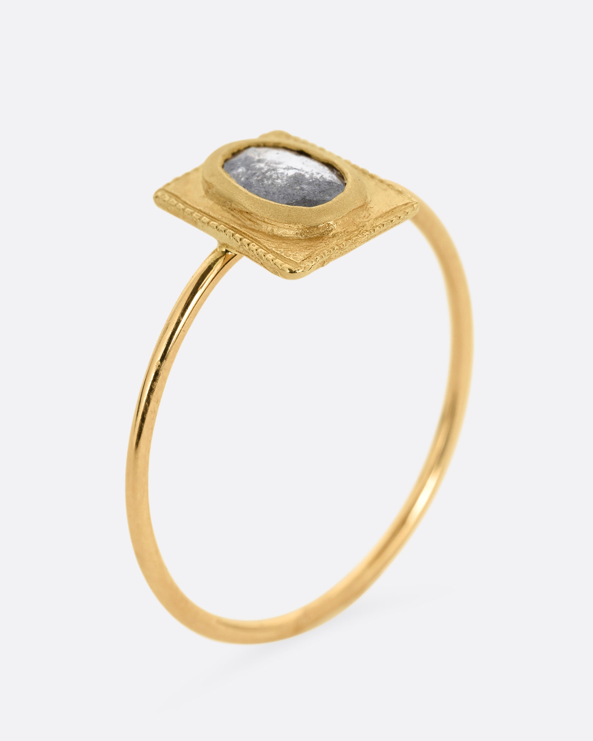 A yellow gold ring with an oval rose cut diamond in a rectangular setting. Shown standing up from the side.