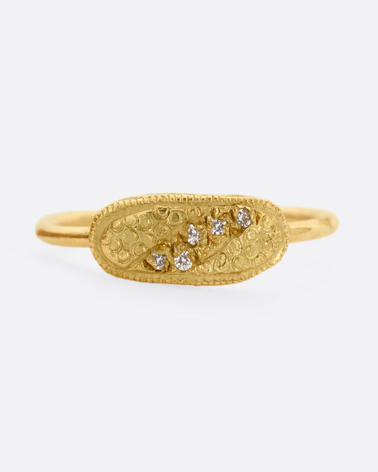 A yellow gold ring with a textural finish and five diamonds. Shown from the front.