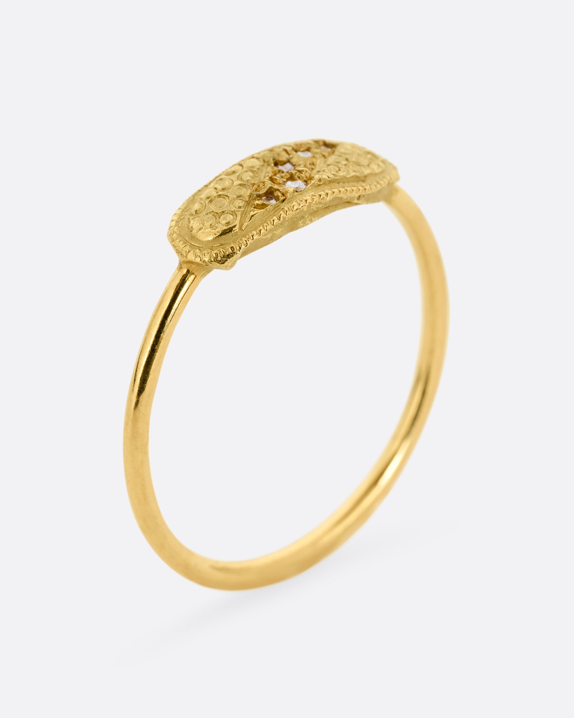 A yellow gold ring with a textural finish and five diamonds. Shown from the side standing up.