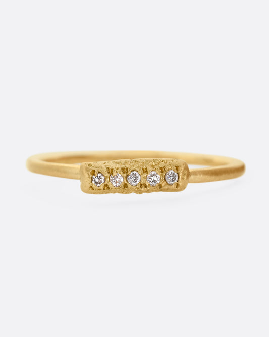 A yellow gold ring with five diamonds set on a textured face. Shown from the front.