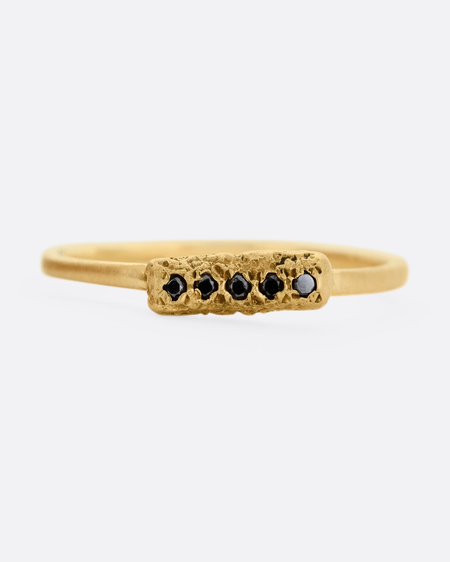 A yellow gold ring with five black diamonds set in a textured rectangular face. Shown from the front.