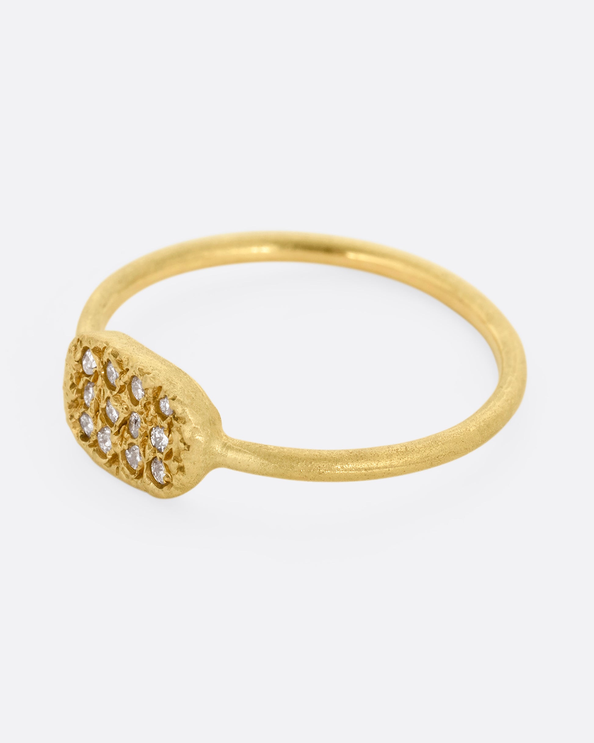 A yellow gold ring with a textured oval face with twelve white diamonds, shown from the side.