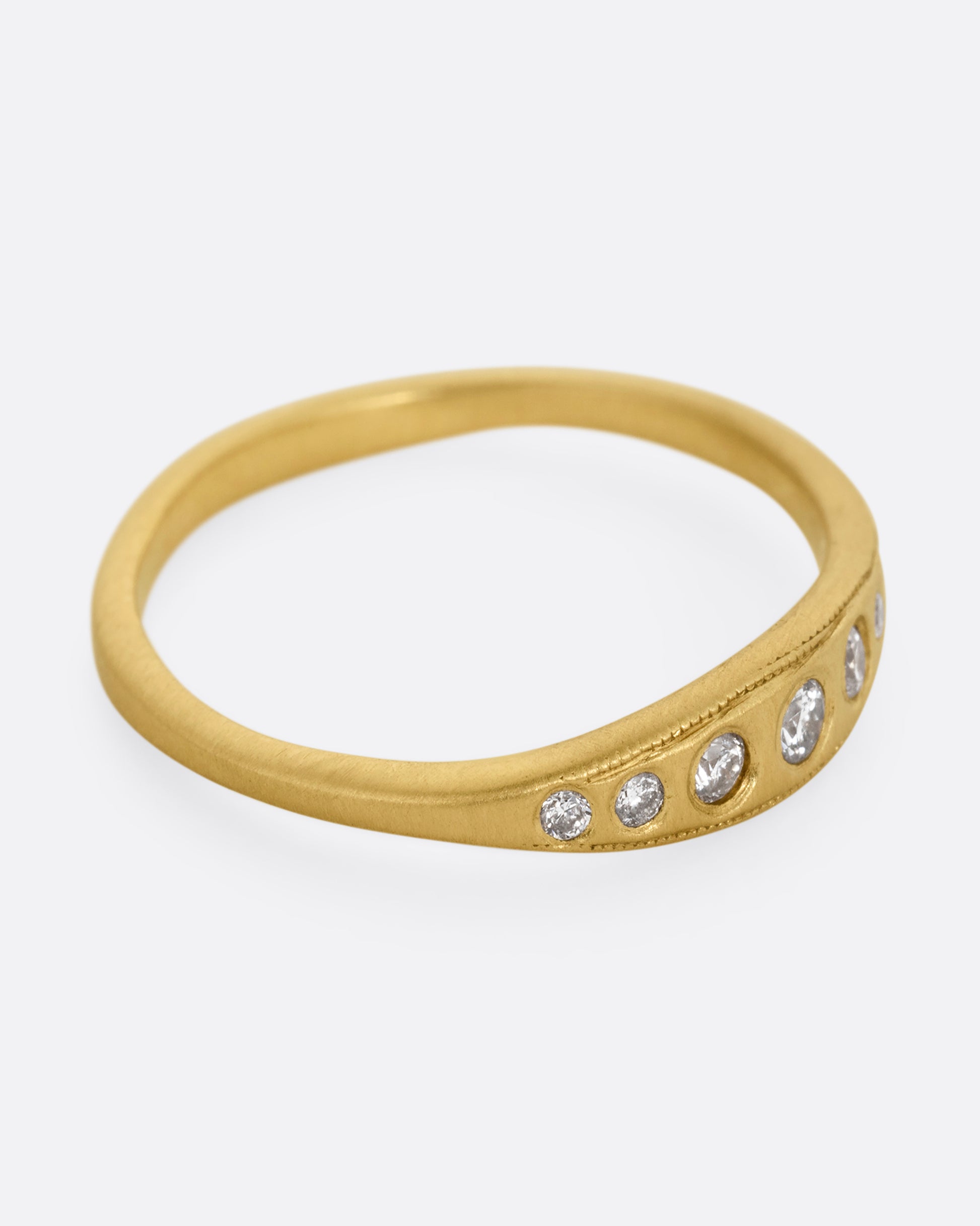 A yellow gold ring with seven diamonds. Shown from the side.