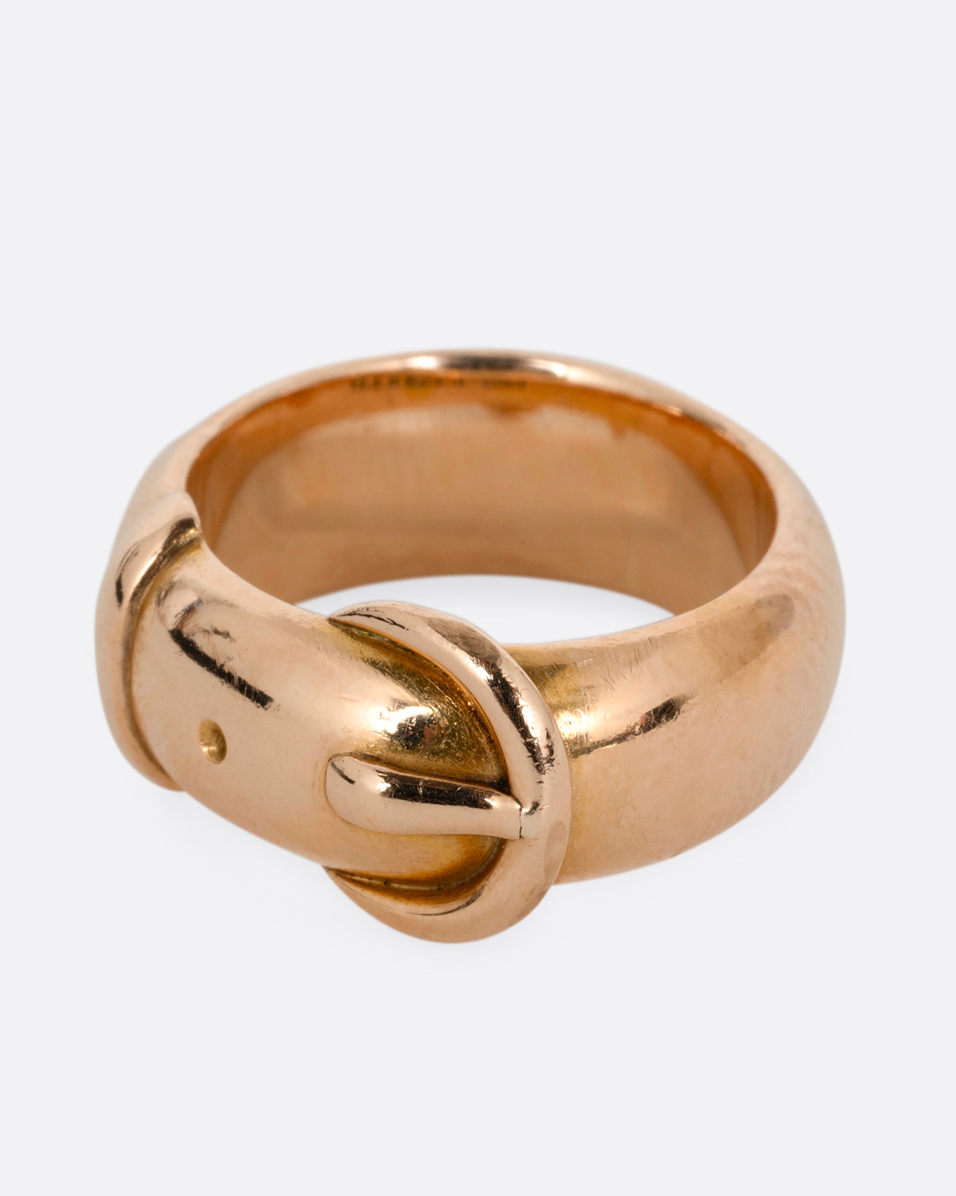 A yellow gold belt buckle ring with a curved edge. Shown from the side.