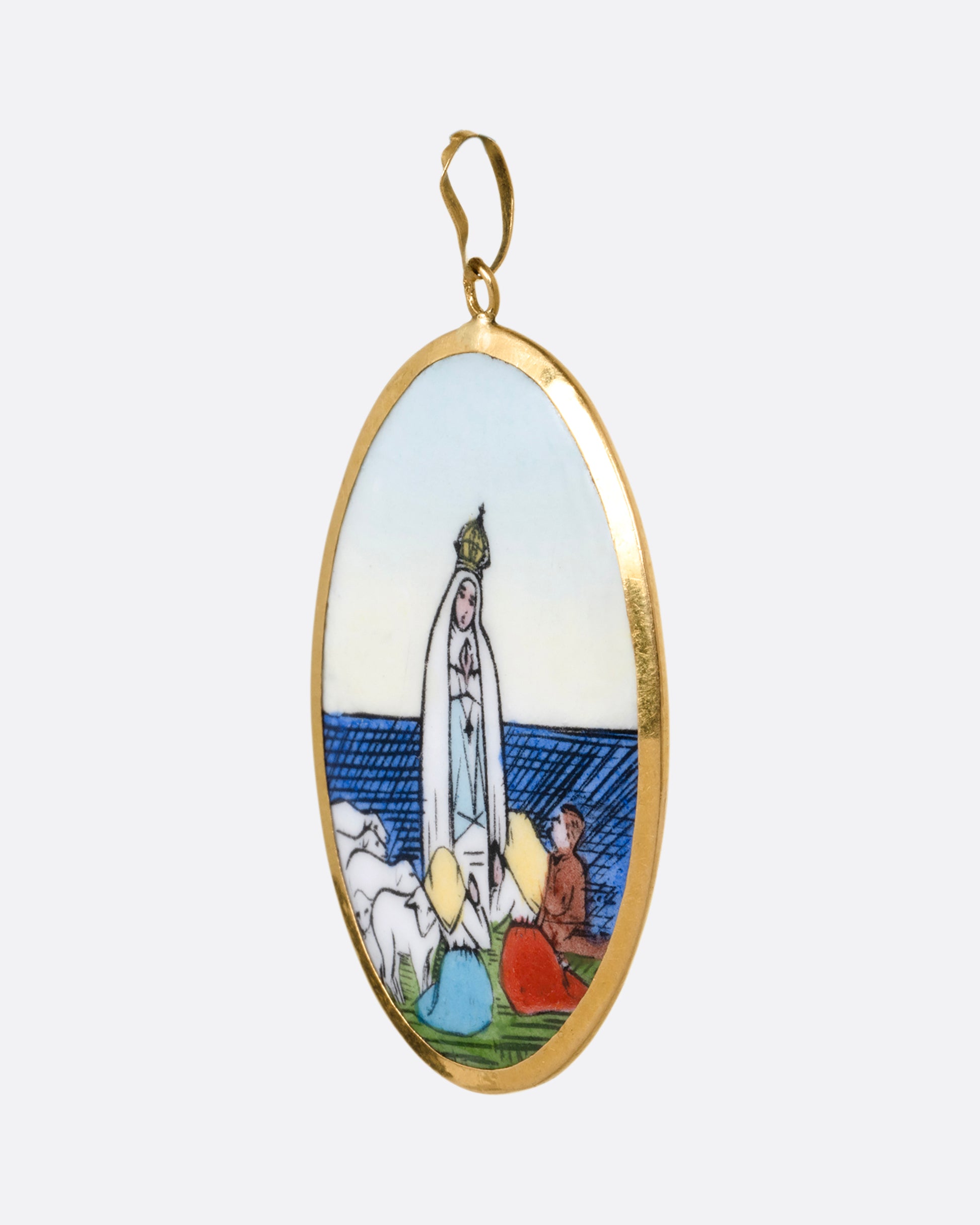 A yellow gold pendant with a hand painted image of the Virgin Mary sits at the center and "Na sa do Rosario da Patima" on its reverse. Shown from the side.