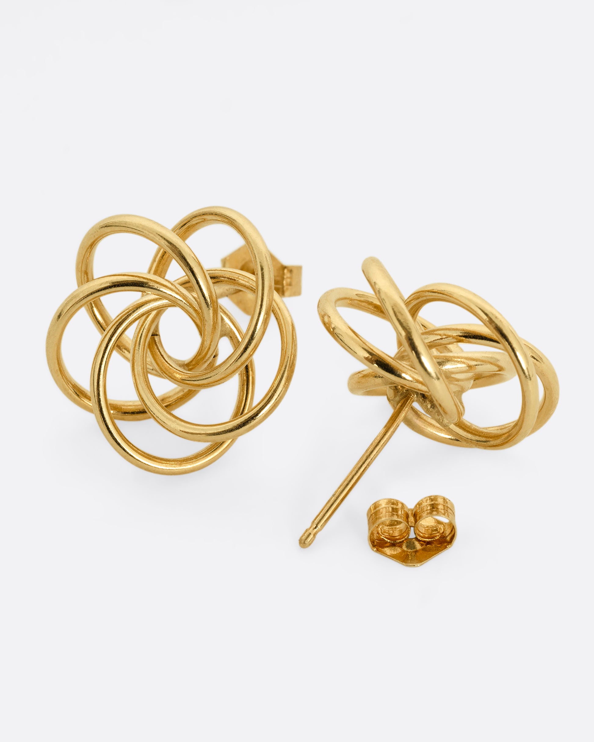 A pair of yellow gold earrings with knotted circles. One earring is shown from the front, the other open from the back.