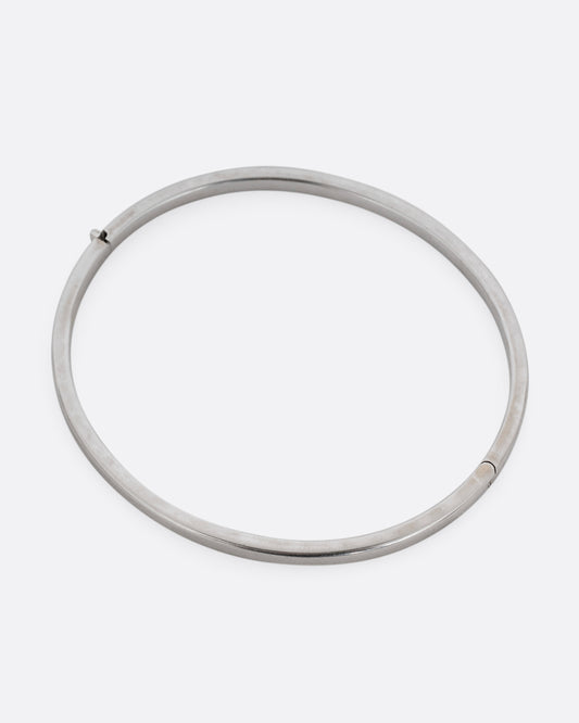 A silver hinged  bangle bracelet with squared edges. Shown from the top.