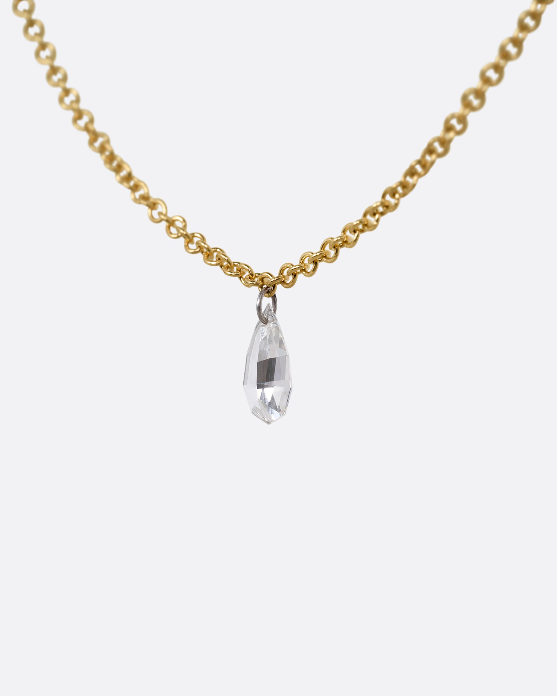 A yellow gold cable chain necklace with a pear shaped diamond. Shown from the side.
