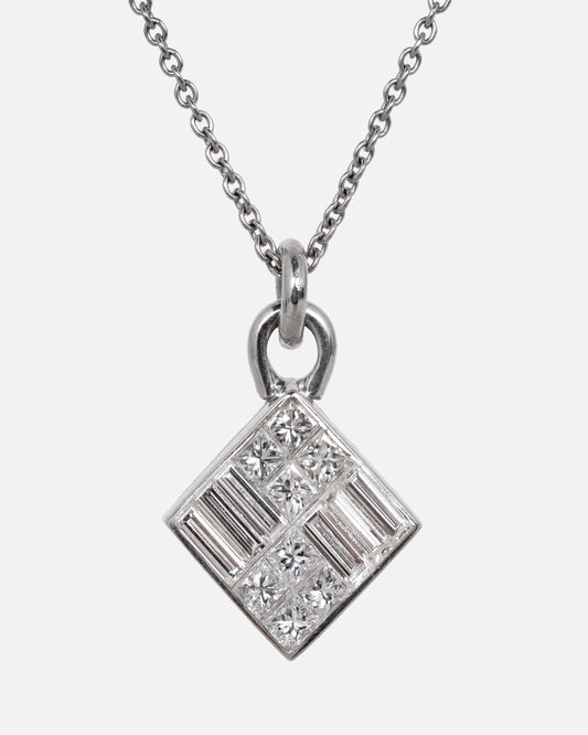 A white gold cable chain necklace with a pendant of princess cut and baguette diamonds. Shown from the front.