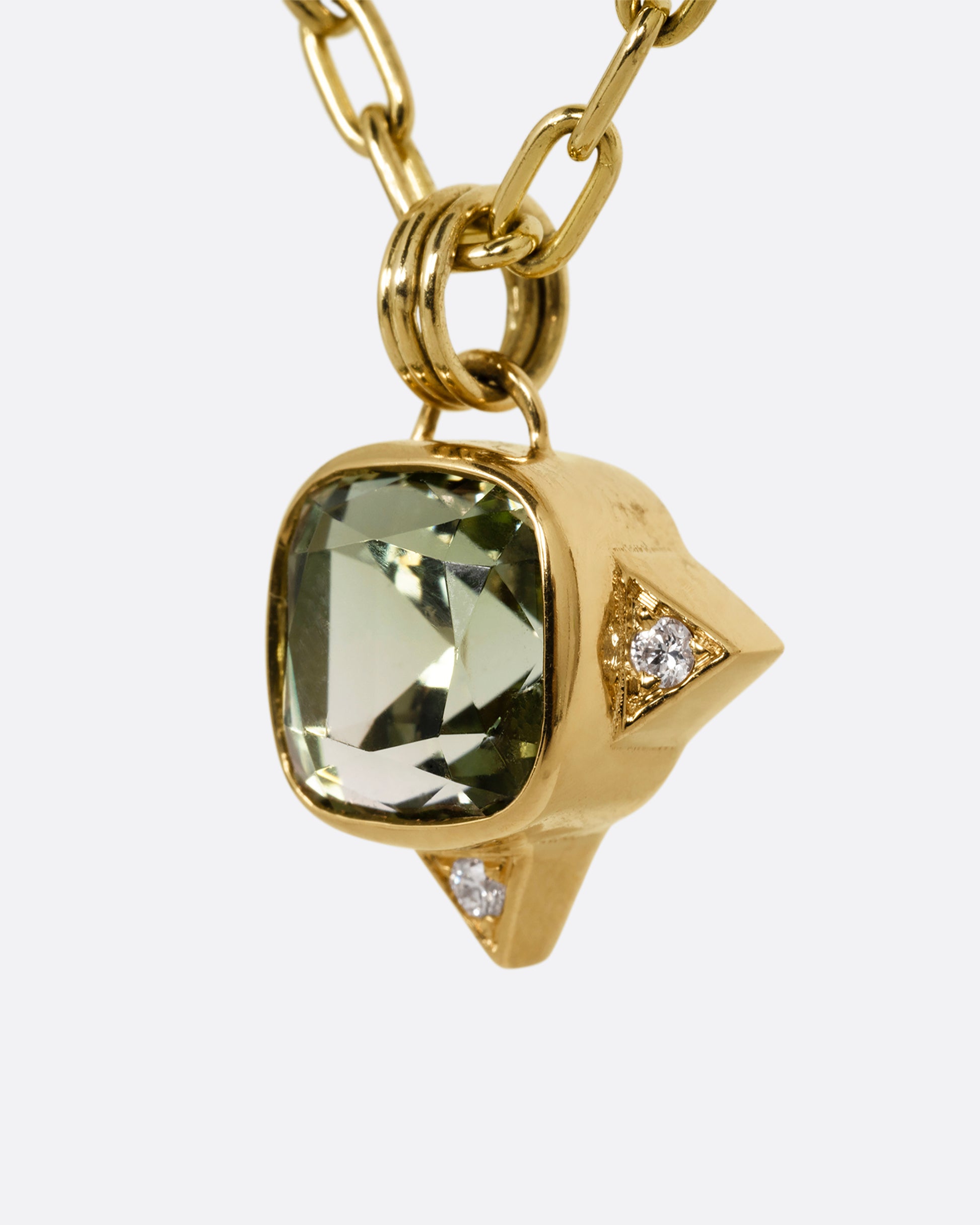 A yellow gold cable chain necklace with a green tourmaline and white diamond accents. Shown from the side.