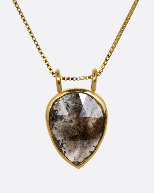 A yellow gold box chain necklace with a pear shaped salt and pepper diamond pendant shown from the front.