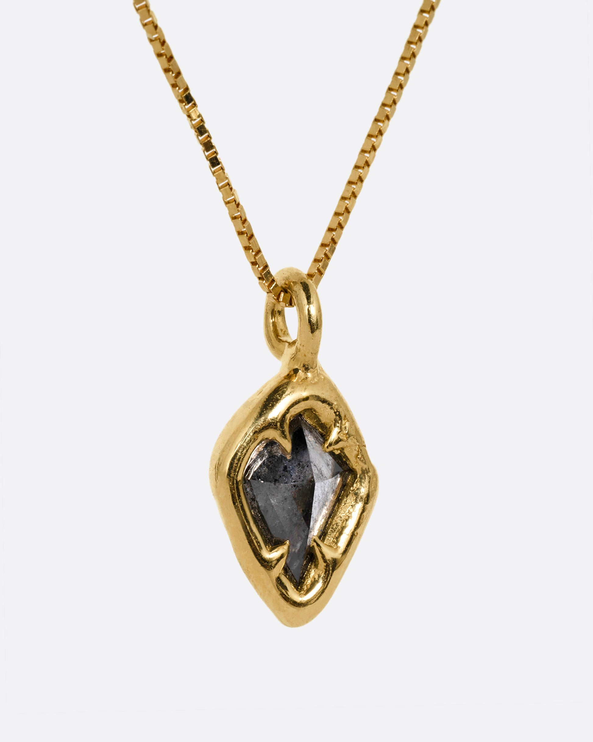 A yellow gold necklace with a kite shaped salt and pepper diamond in a claw setting. Shown from the side.
