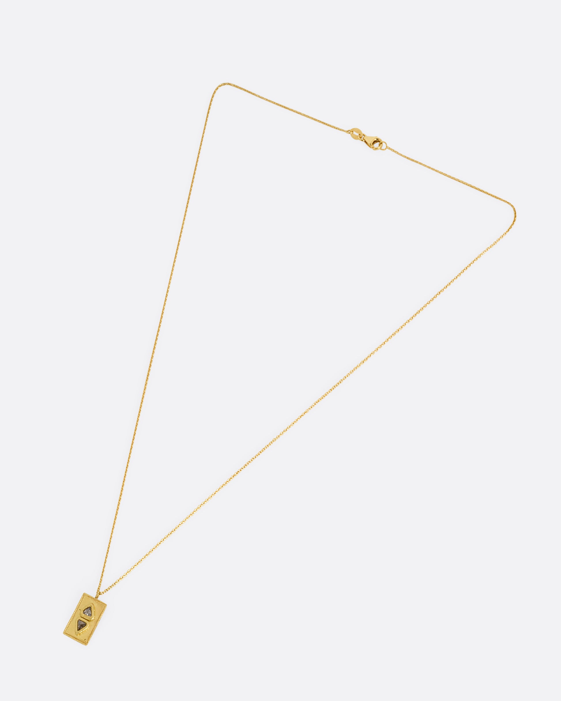 A cable chain necklace with two triangle shaped salt and pepper diamonds in a rectangle pendant. Shown from the front.