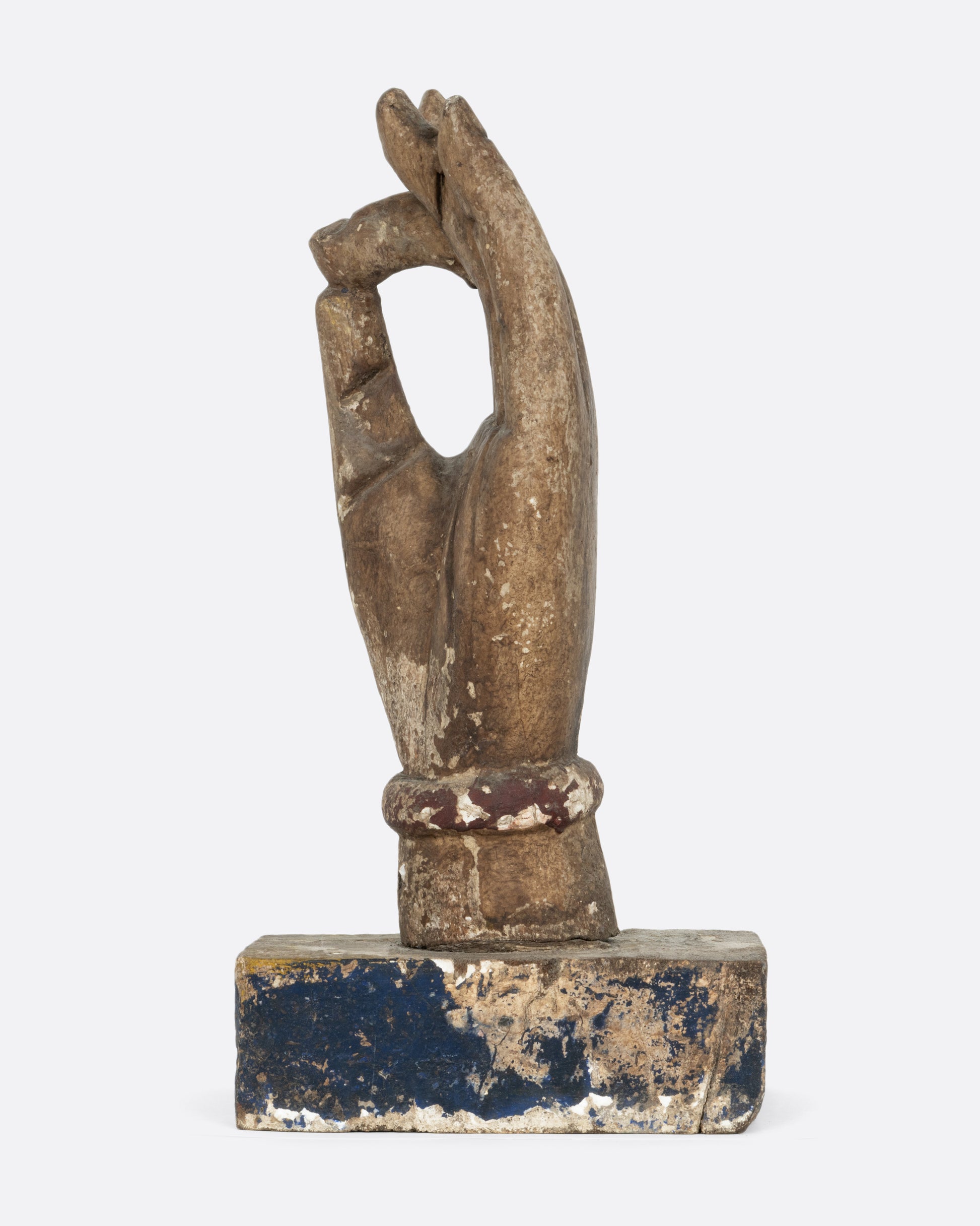 A wooden hand sculpture with the index and thumb touching. Shown from the side.