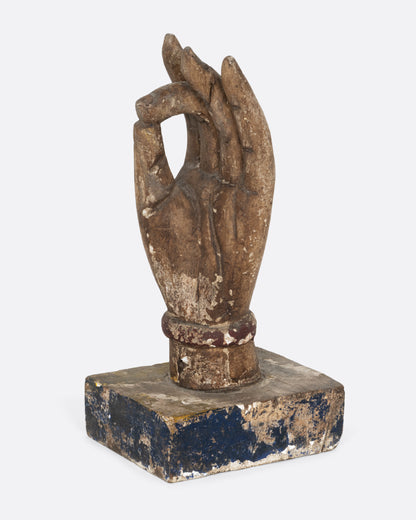 A wooden hand sculpture with the index and thumb touching. Shown from the side.