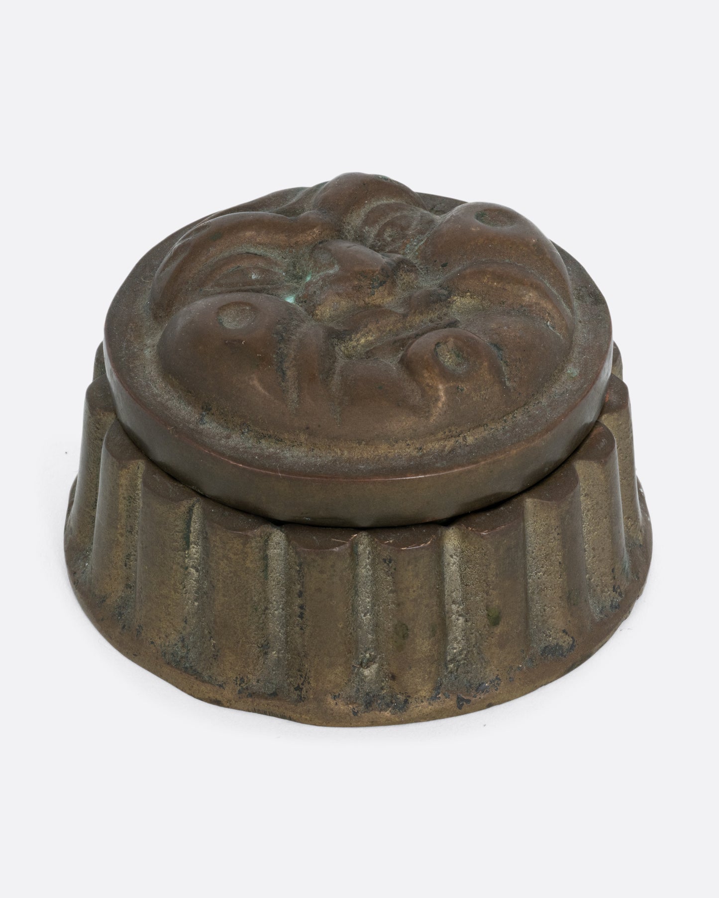 A round box with a face on the lid and ridged sides. Shown from the front.