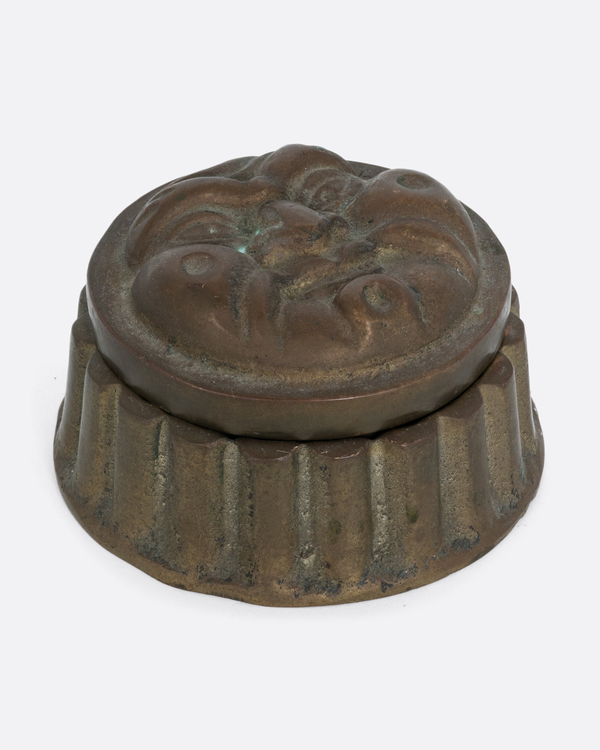 A round box with a face on the lid and ridged sides. Shown from the front.