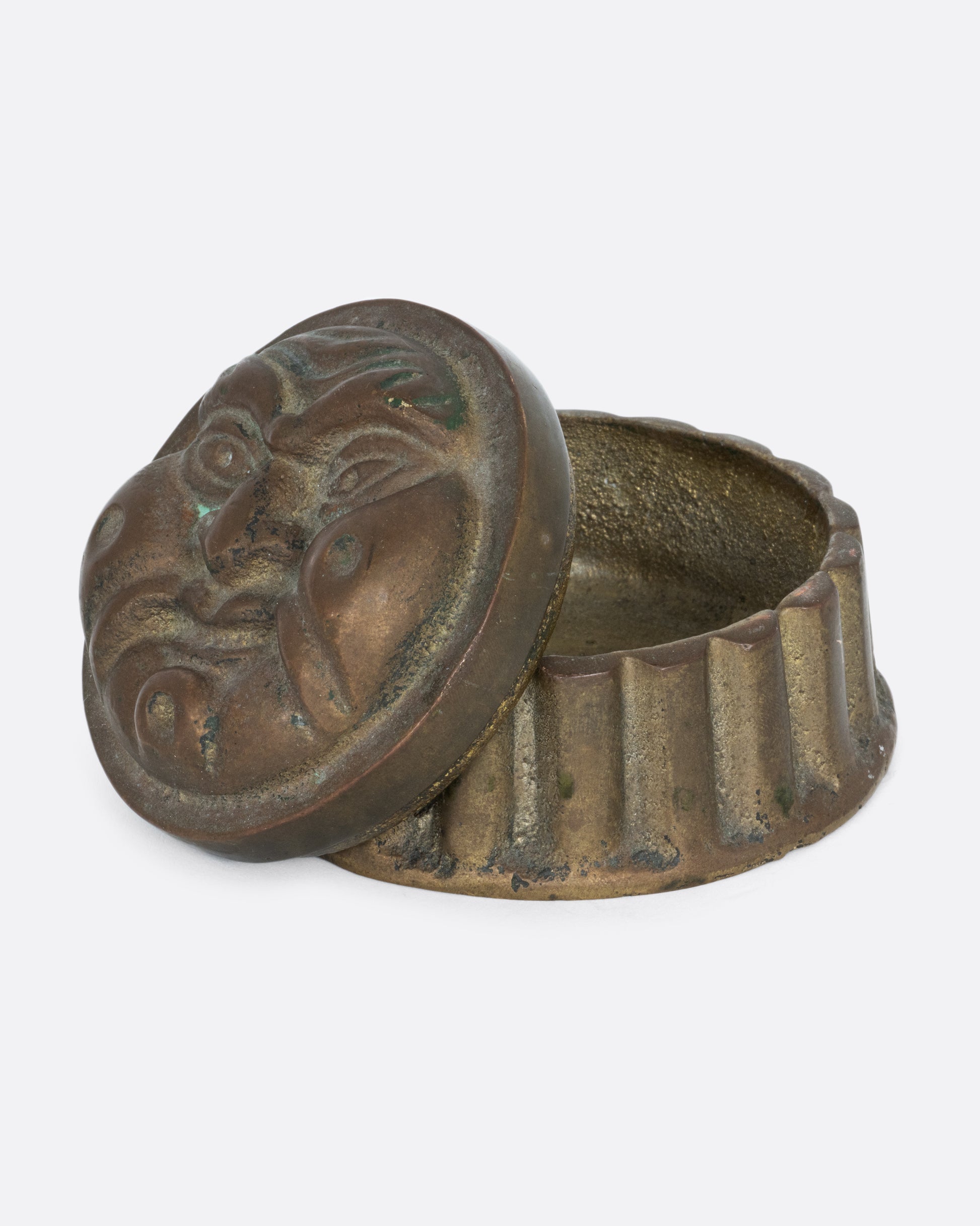 A round box with a face on the lid and ridged sides. Shown open from the side.