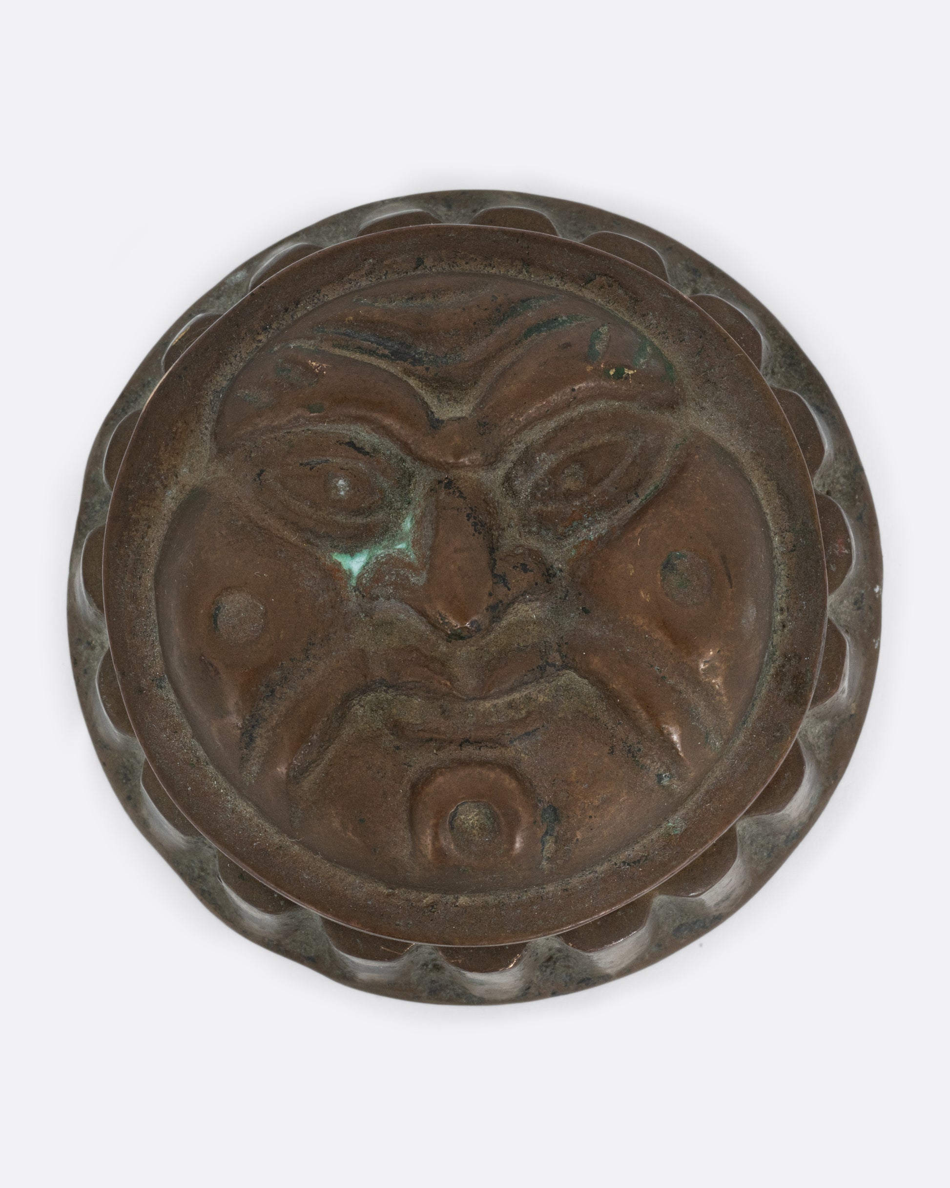 A round box with a face on the lid and ridged sides. Shown from the top.