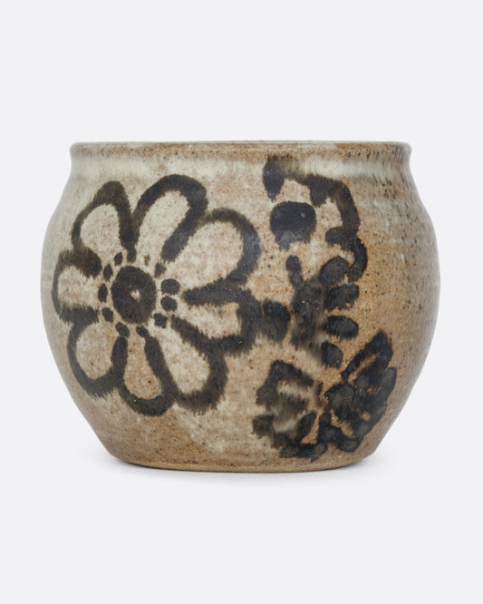 A pot with a brown handpainted pattern of flowers and a drainage hole at its base. Shown from the front.