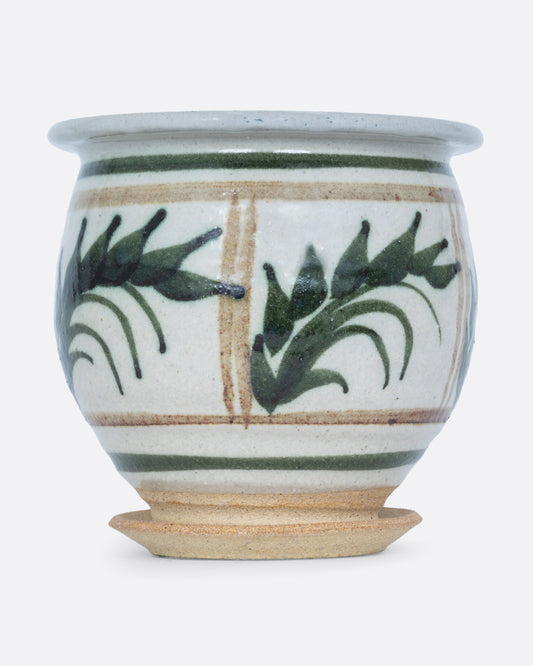 A planter with a hand painted botanical pattern and a drainage hole, water catch, and felted bottom. Shown from the front.
