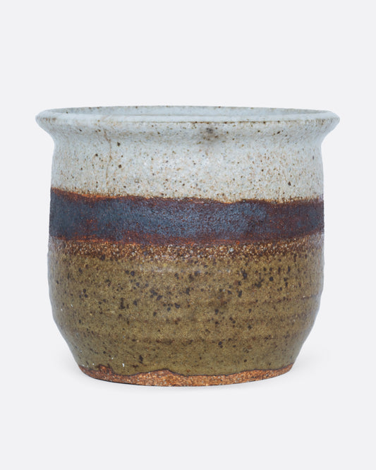 A planter with a striped glaze and drainage hole at its base. Shown from the front.