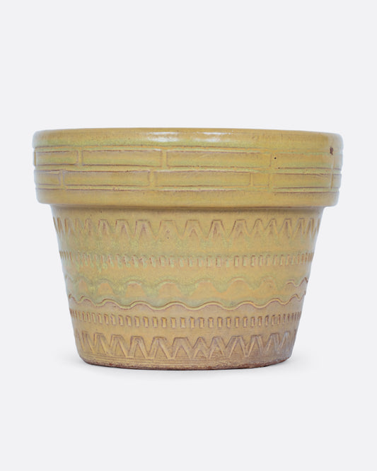 A terracotta planter with a textural stamped pattern and a drainage hole at its base. Shown from the side.