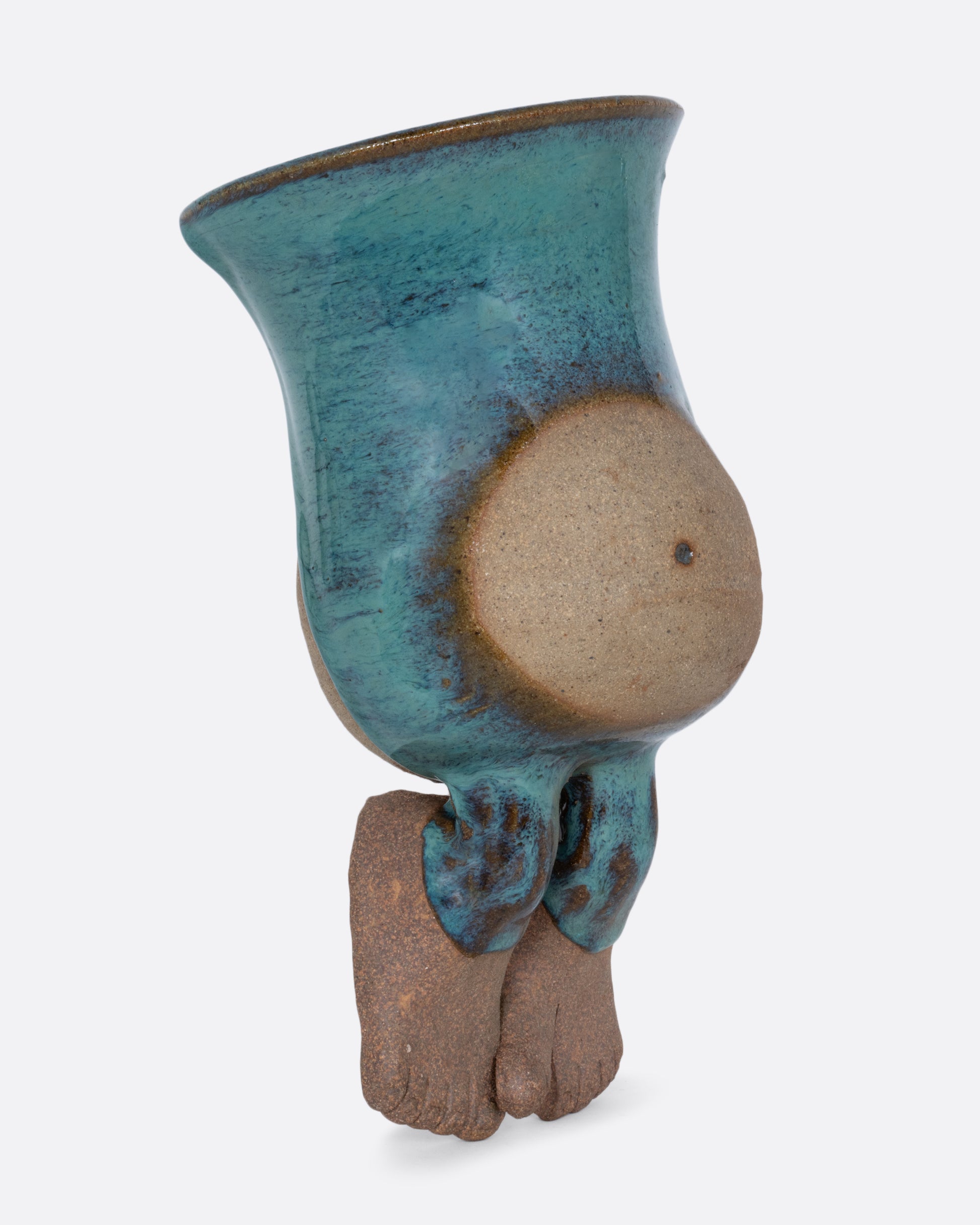 A ceramic wall pocket sculpture of a torso with a belly and feet. Shown from the side.