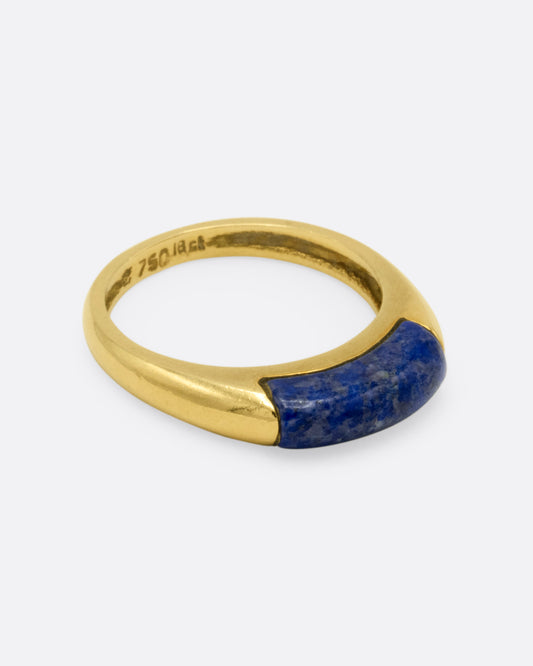 A yellow gold signet ring with a rounded silhouette and bar of lapis, shown from the side.