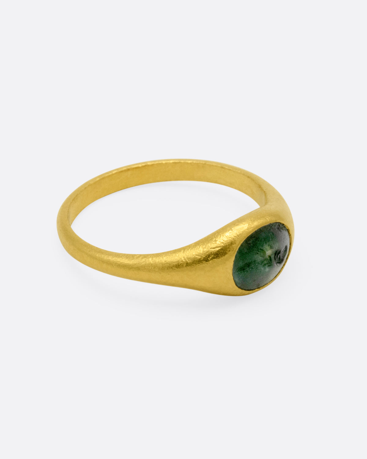 A yellow gold signet ring with a dark green chalcedony carved with a parrot, shown from the side.