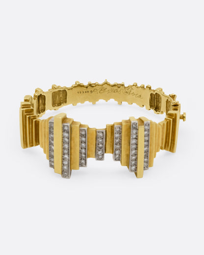 A yellow gold cuff bracelet with queues of diamonds and white gold accents, shown from the side.