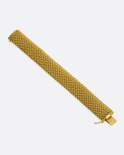 A wide woven yellow gold bracelet, shown from the front.
