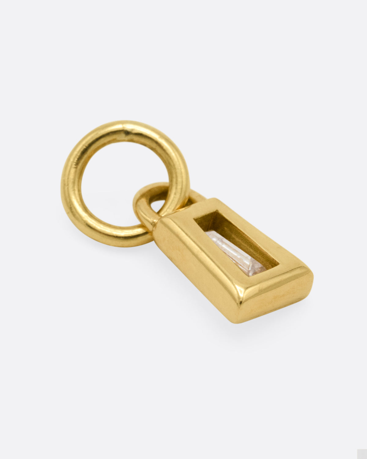 A yellow gold charm with a tapered baguette diamond, shown from the back.