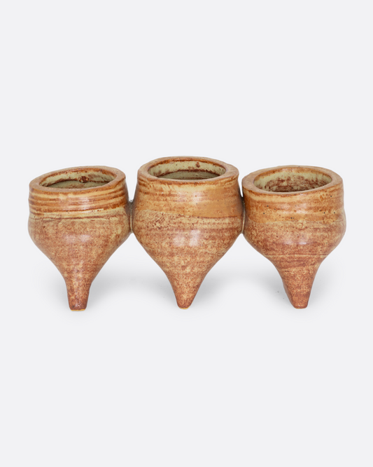 Three connected planters with pinched bottoms, drainage holes, and feet. Shown from the side.