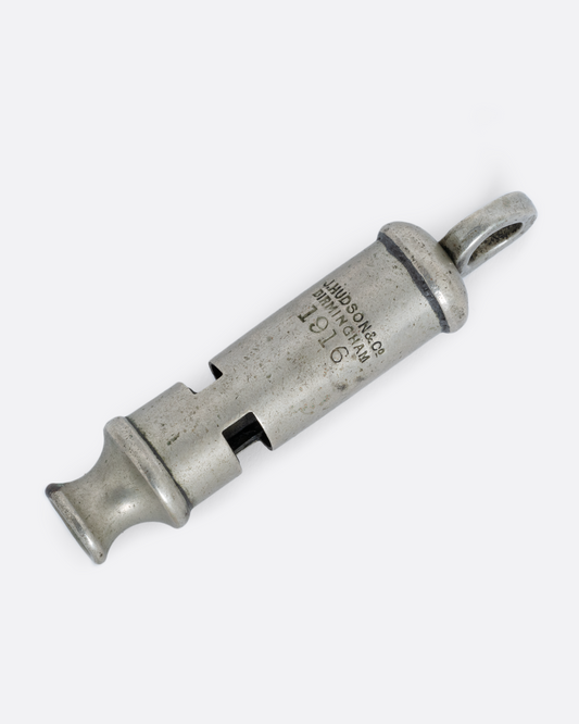 A silver whistle with engraved text, shown from the back.