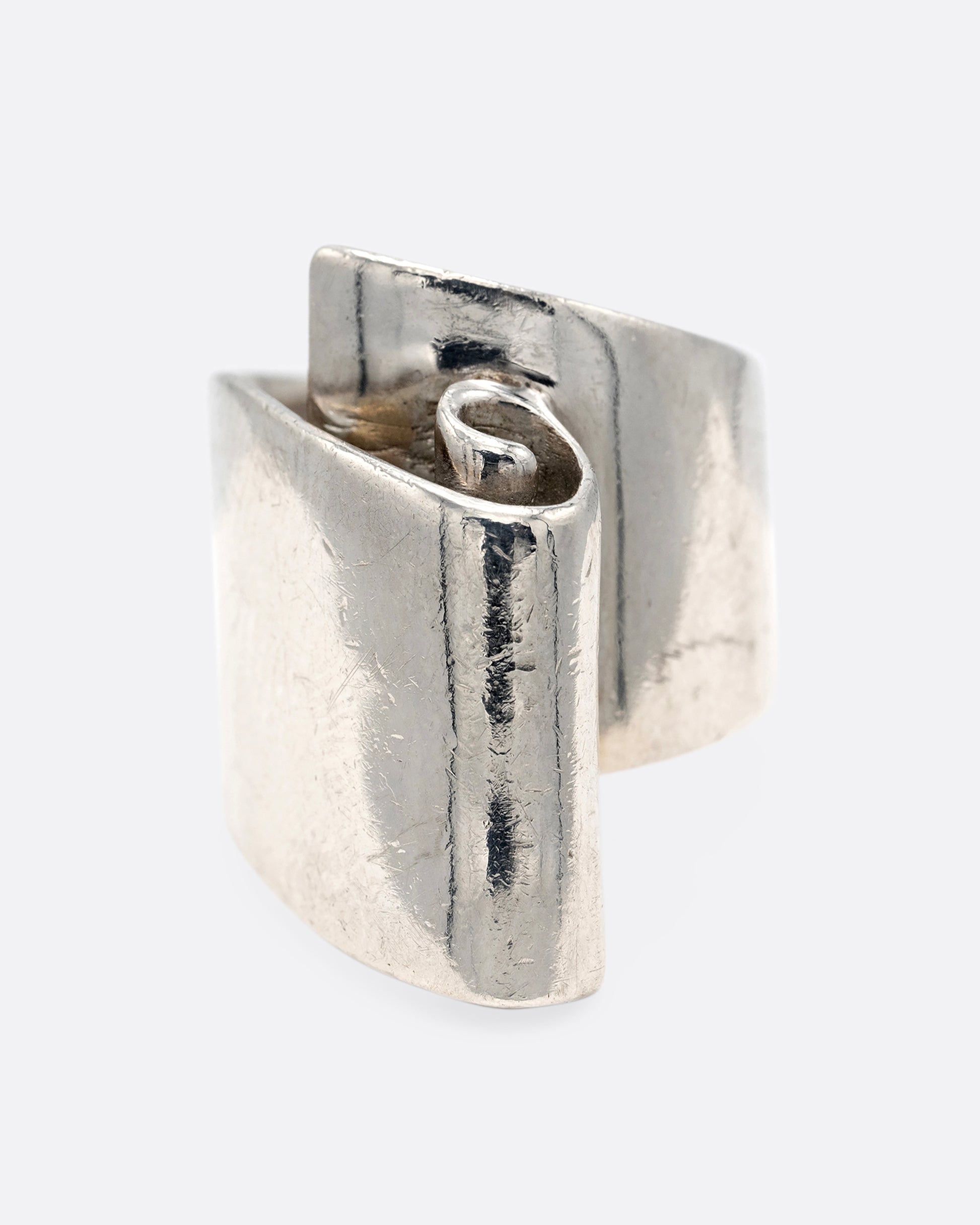 A silver ring with a scroll on its face. Shown from the front.