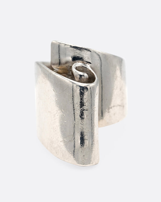 A silver ring with a scroll on its face. Shown from the front.