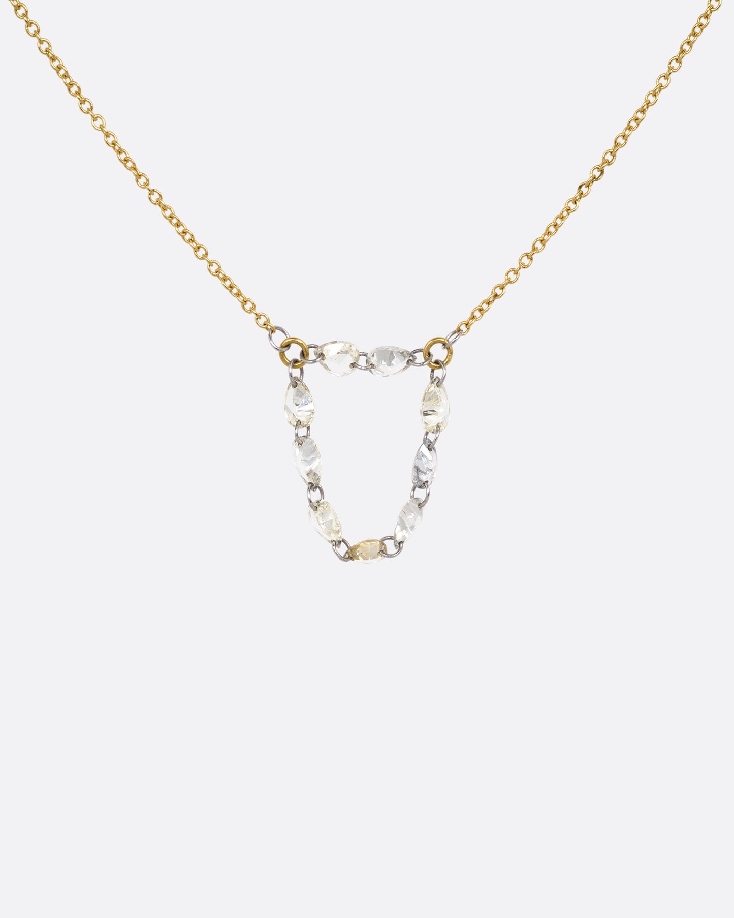 A yellow gold cable chain necklace with a loop of nine rose cut diamonds at the center. Shown from the front.