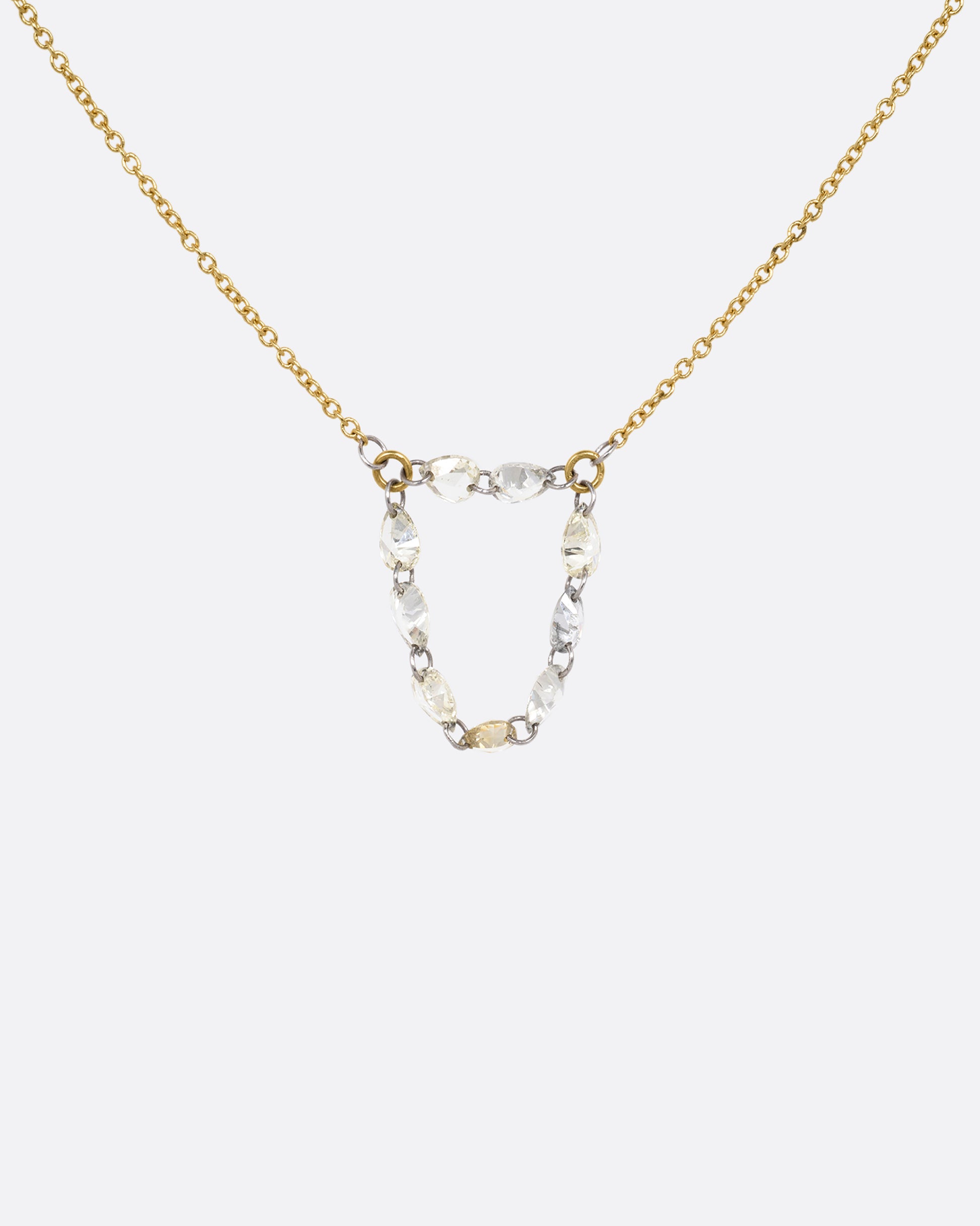 A yellow gold cable chain necklace with a loop of nine rose cut diamonds at the center. Shown from the front.