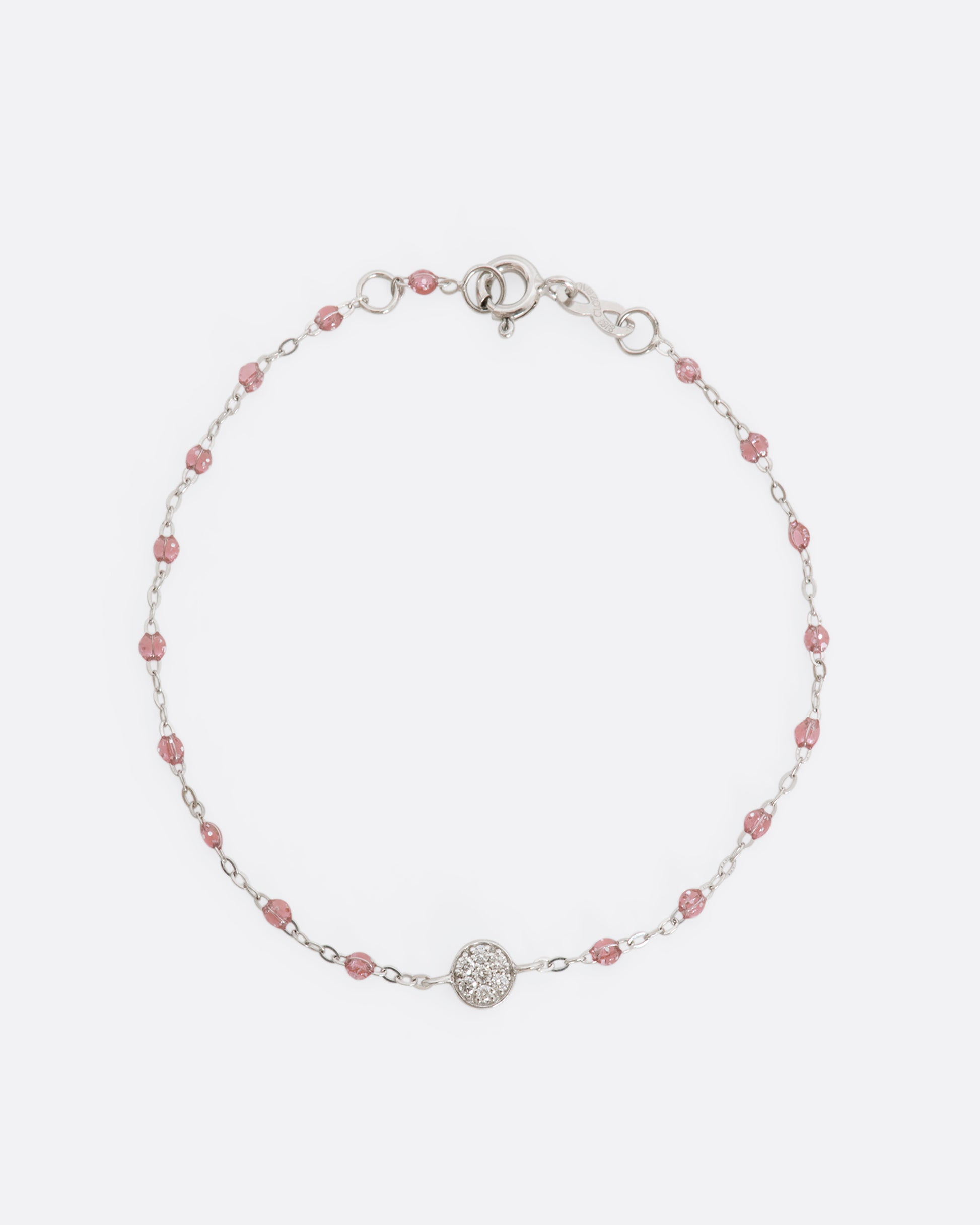 A white gold bracelet with rose pink glitter resin beads and a pave diamond disc and the center. View from above laying flat.