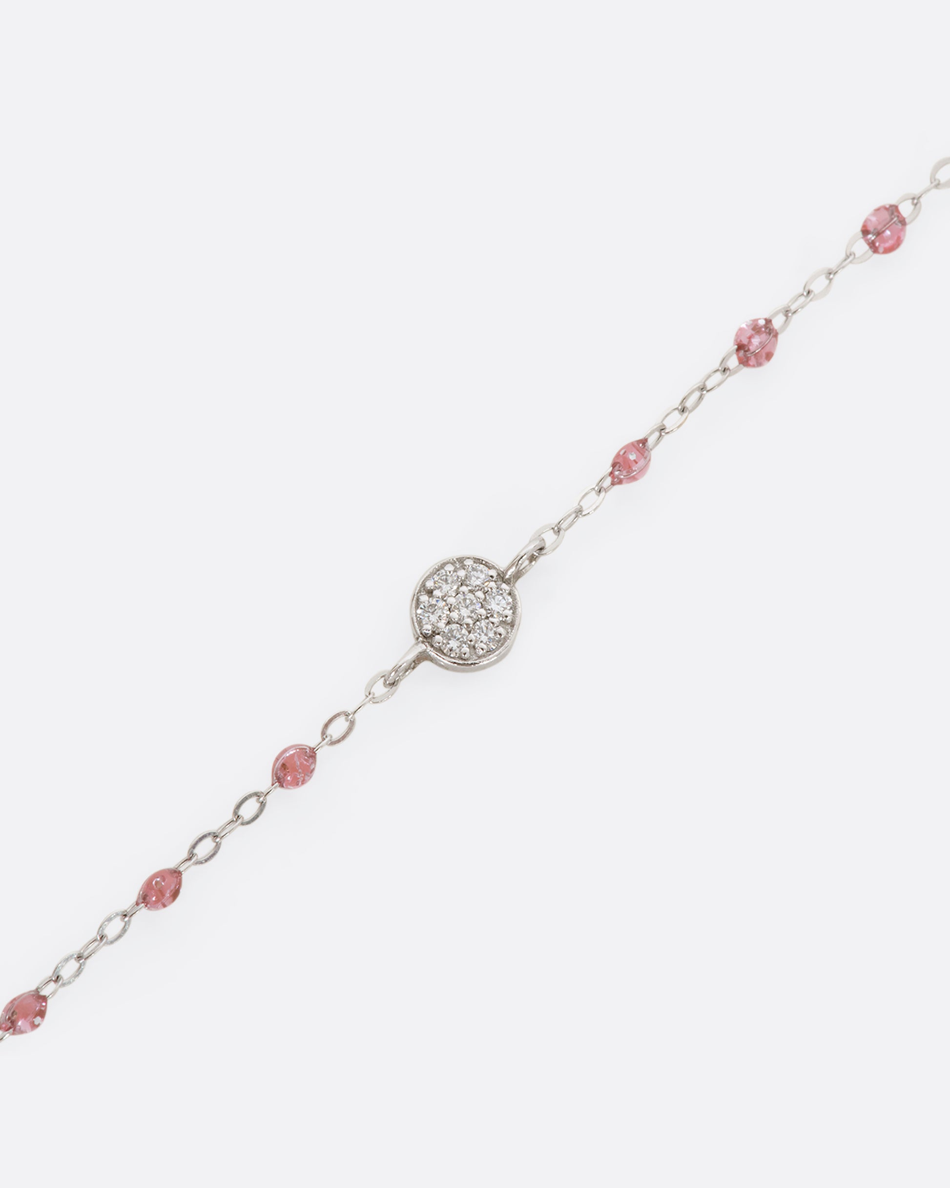 A white gold bracelet with rose pink glitter resin beads and a pave diamond disc and the center. View close up of diamonds.